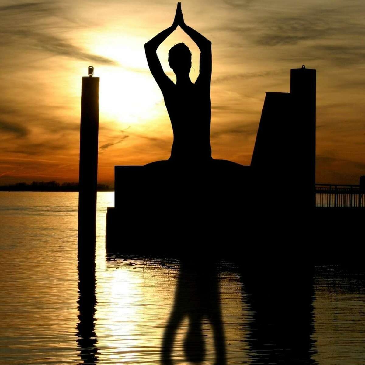 Silhouette en posture de méditation face à la mer au coucher du soleil